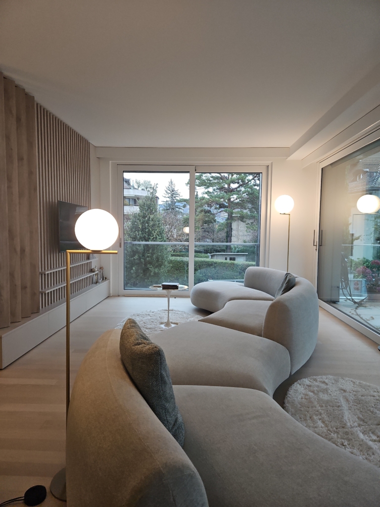 Un salon avec un canapé, une lampe et une fenêtre.